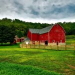 Vibrant red barn amidst lush greenery and cloudy skies in Wisconsin.